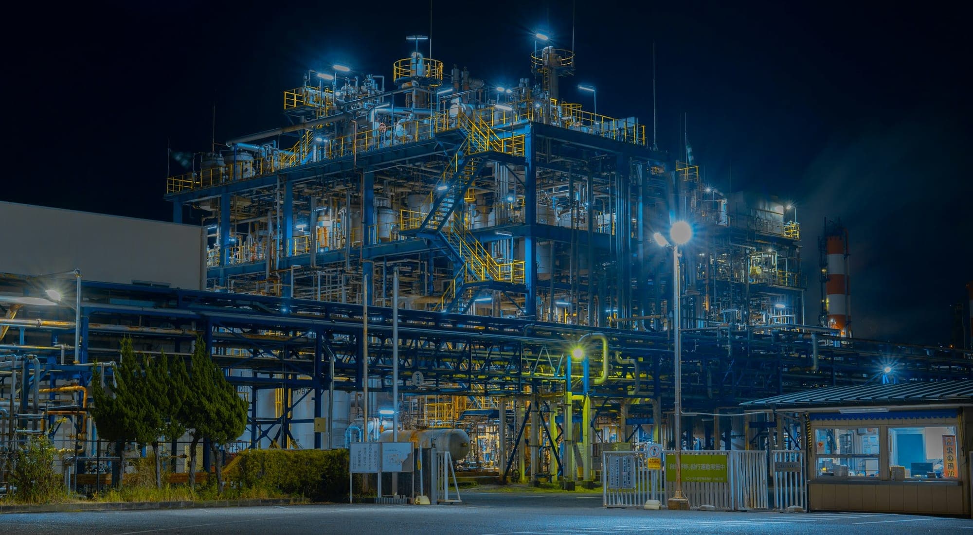 A process plant lit at night, steelwork and pipe racks picked out against a dark sky