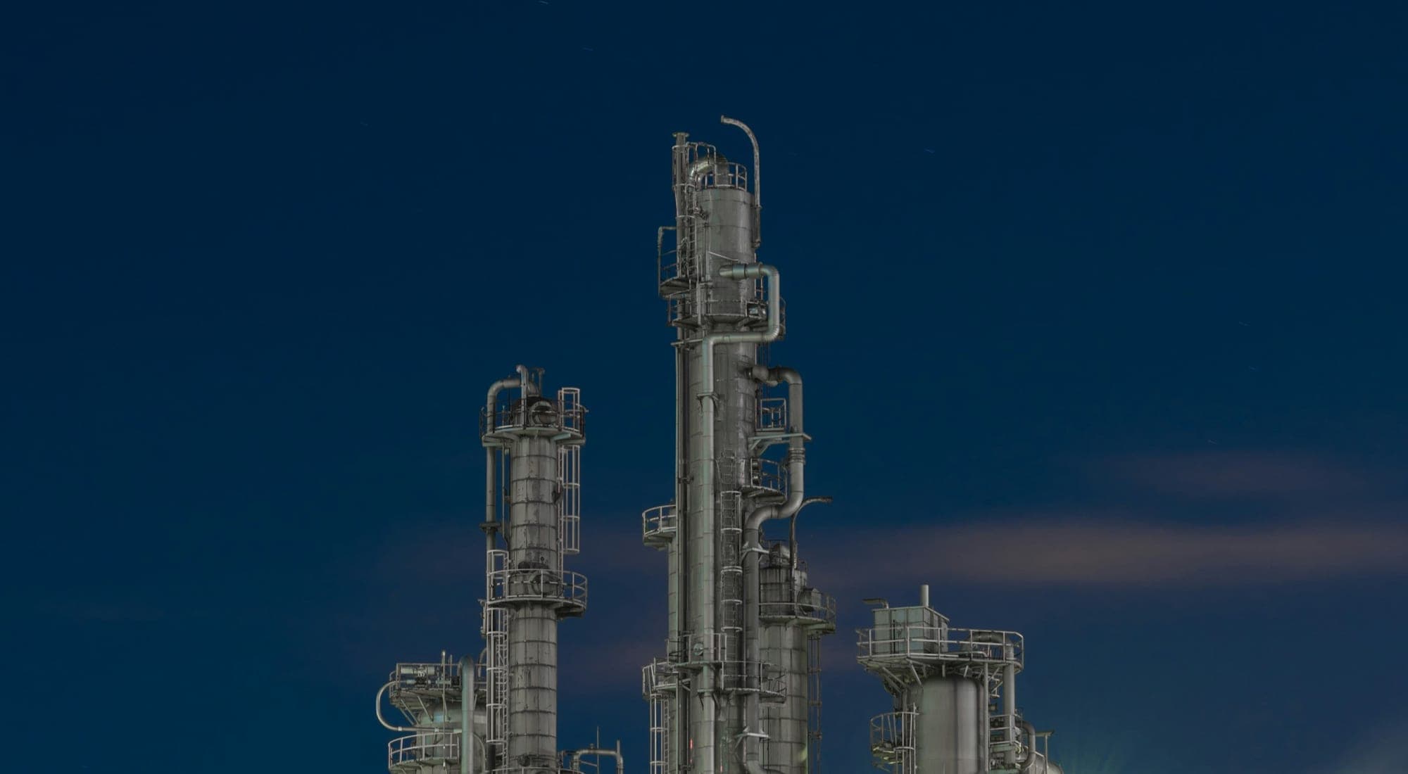 Distillation columns of a process plant against a deep blue dusk sky